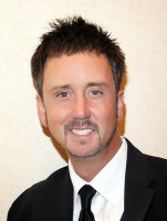 A man in a suit and tie smiling for the camera.