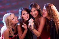 Four women are posing for a picture with one holding a microphone.