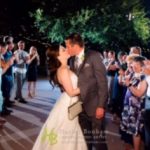 A bride and groom kissing in front of a crowd.