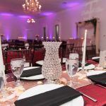 A table set with plates and silverware, napkins, candles and vases.