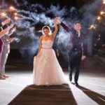 A bride and groom are holding their hands up in the air.