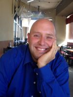 A man with bald head smiling for the camera.