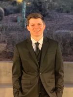 A man in suit and tie standing outside.